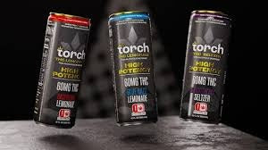 Three slim black cans of Torch cannabis beverages with Lemonade and Seltzer flavors, featuring bold text highlighting high potency and THC content, displayed on a dark surface.